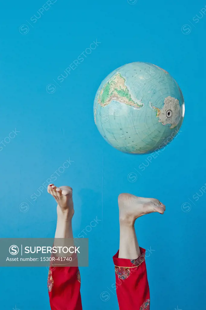 Feet kicking globe in air,