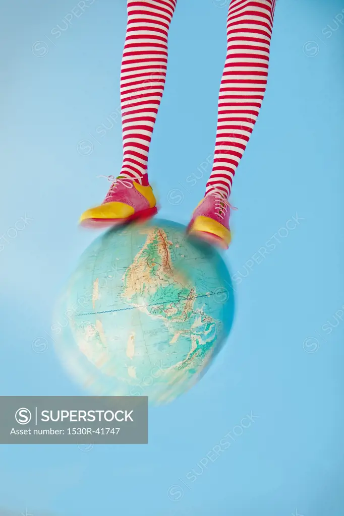 Legs in striped socks with colorful shoes on globe,