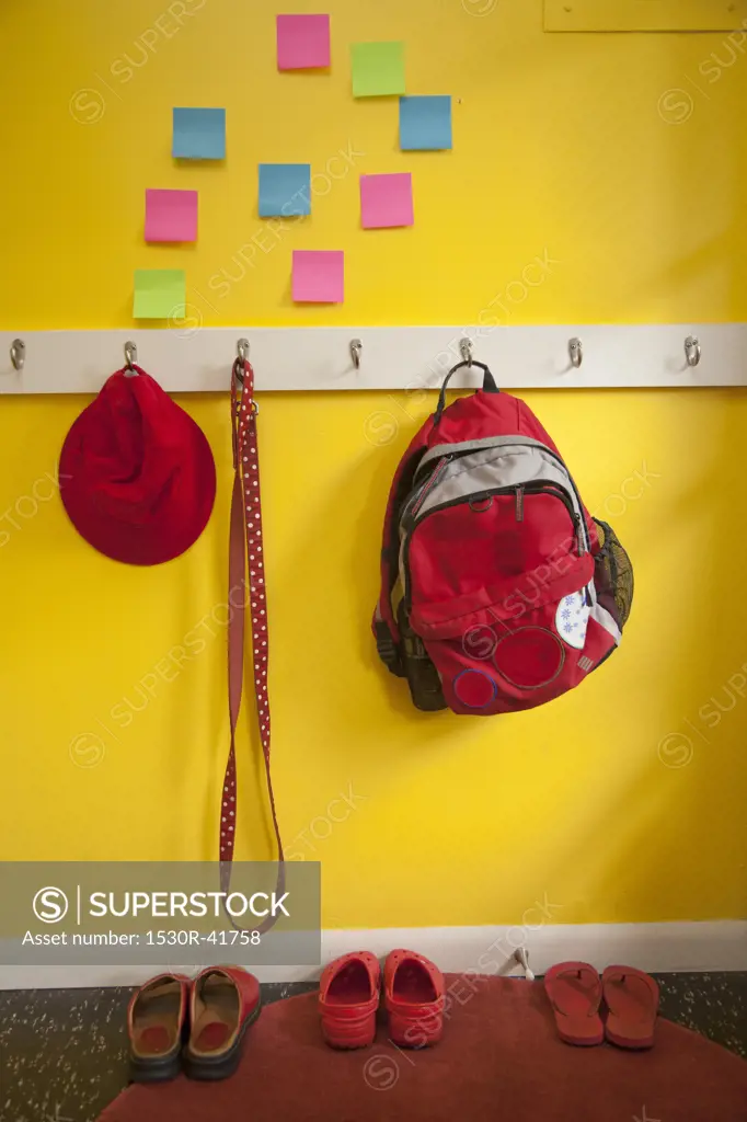 Yellow wall with colorful post-its and loaded coat hooks,