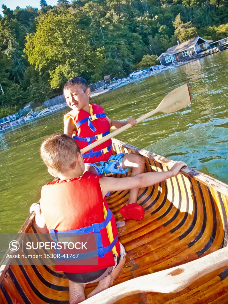 Two young boys paddling canoe,