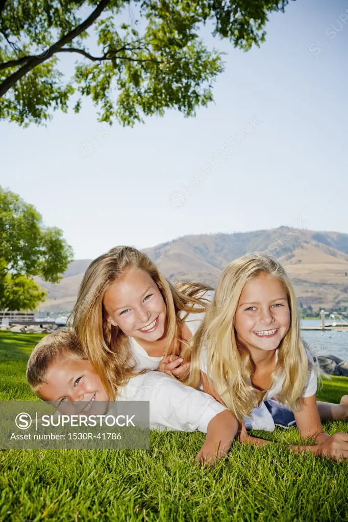 Three young children playing in lakeside park,