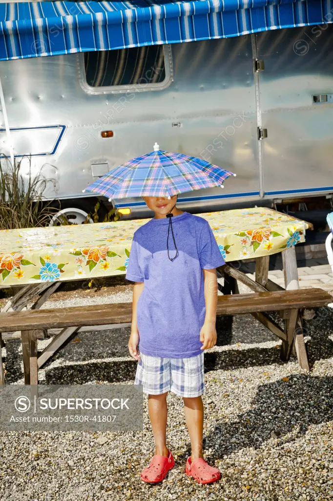 Boy in rain hat near airstream camper,