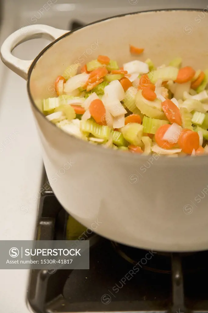 White pot with vegetables on stove,