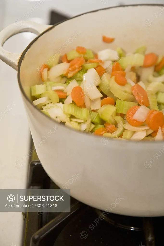 White pot with vegetables on stove,