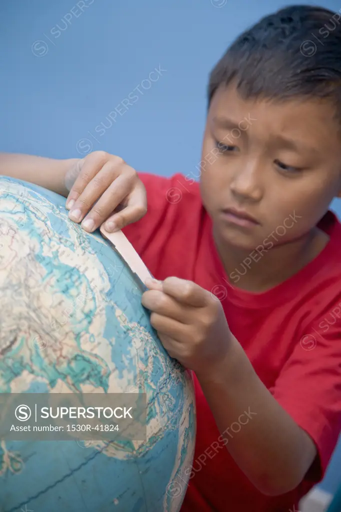 Boy placing bandaid on globe,