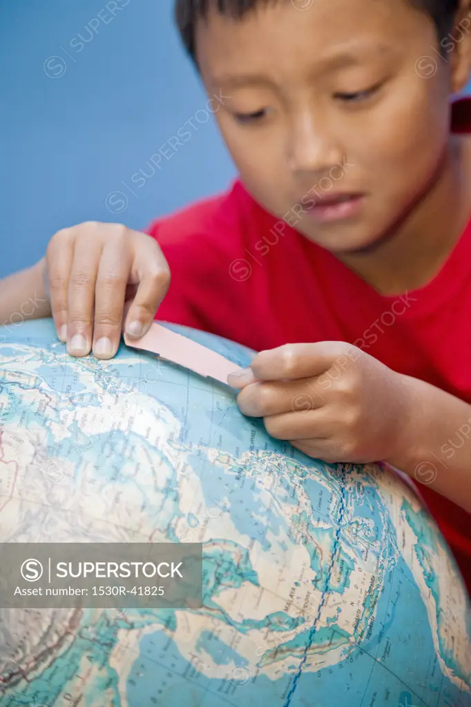 Boy placing bandaid on globe,