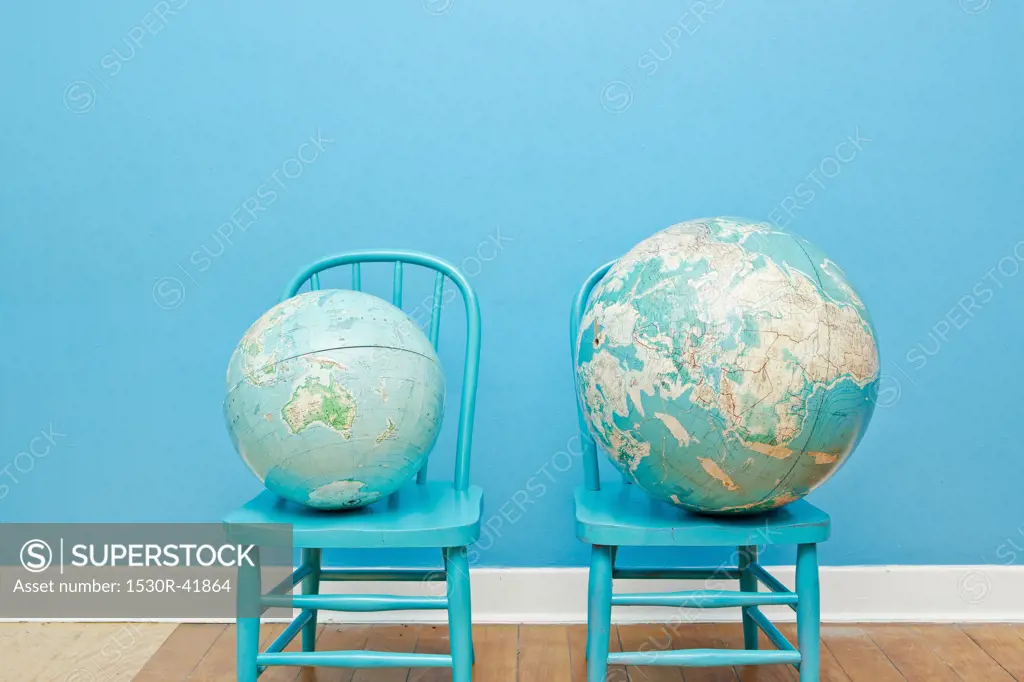 Two globes placed on two chairs,