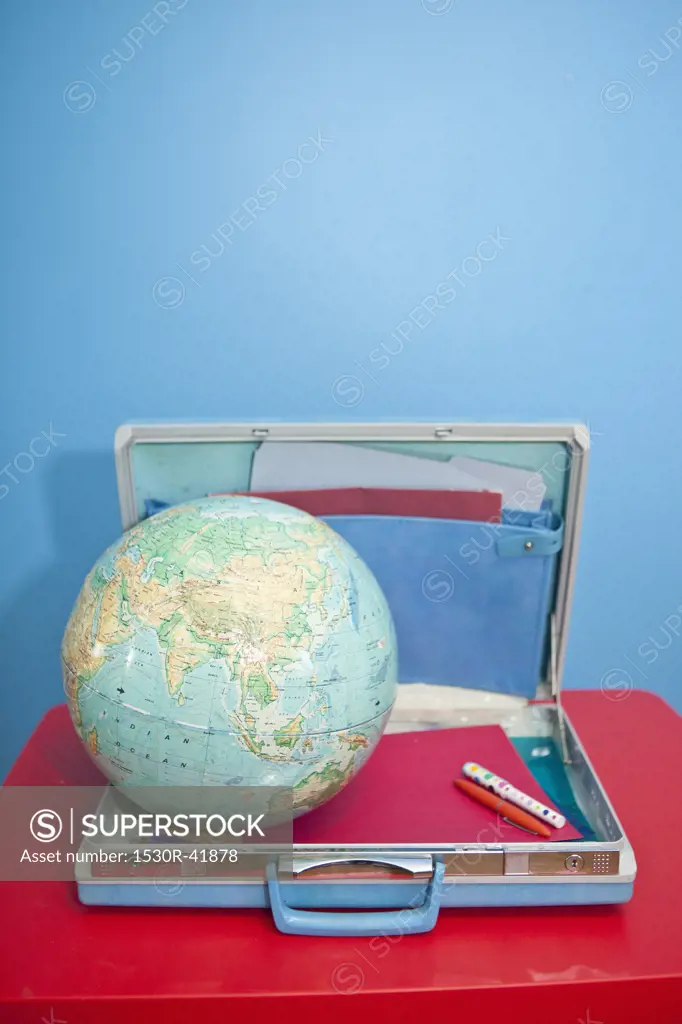 Globe sitting inside open vintage briefcase