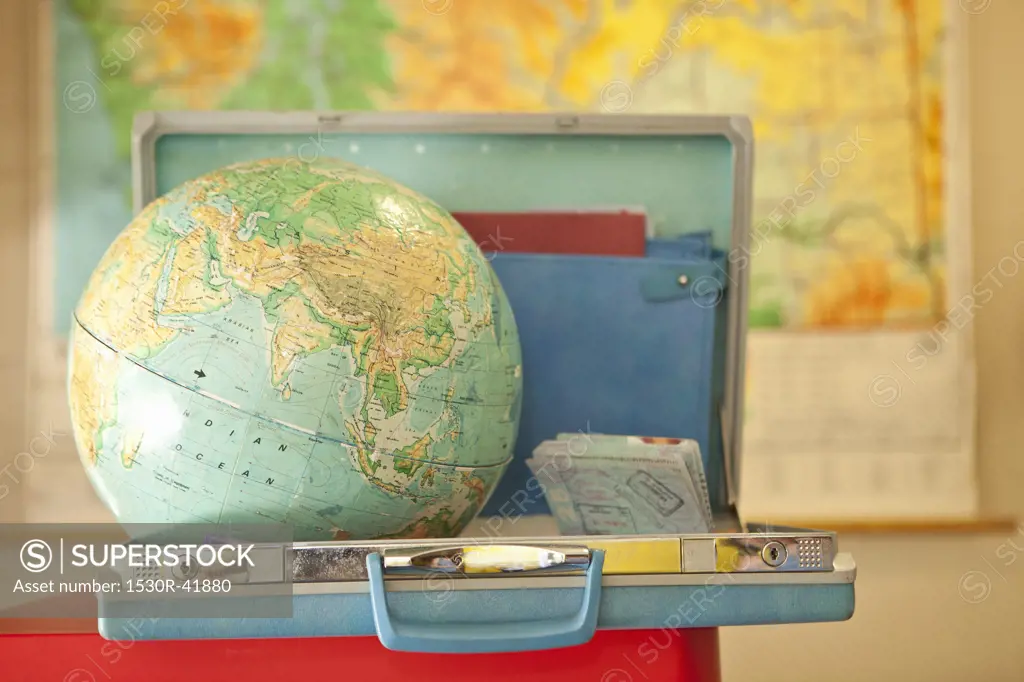 Globe sitting inside open vintage briefcase