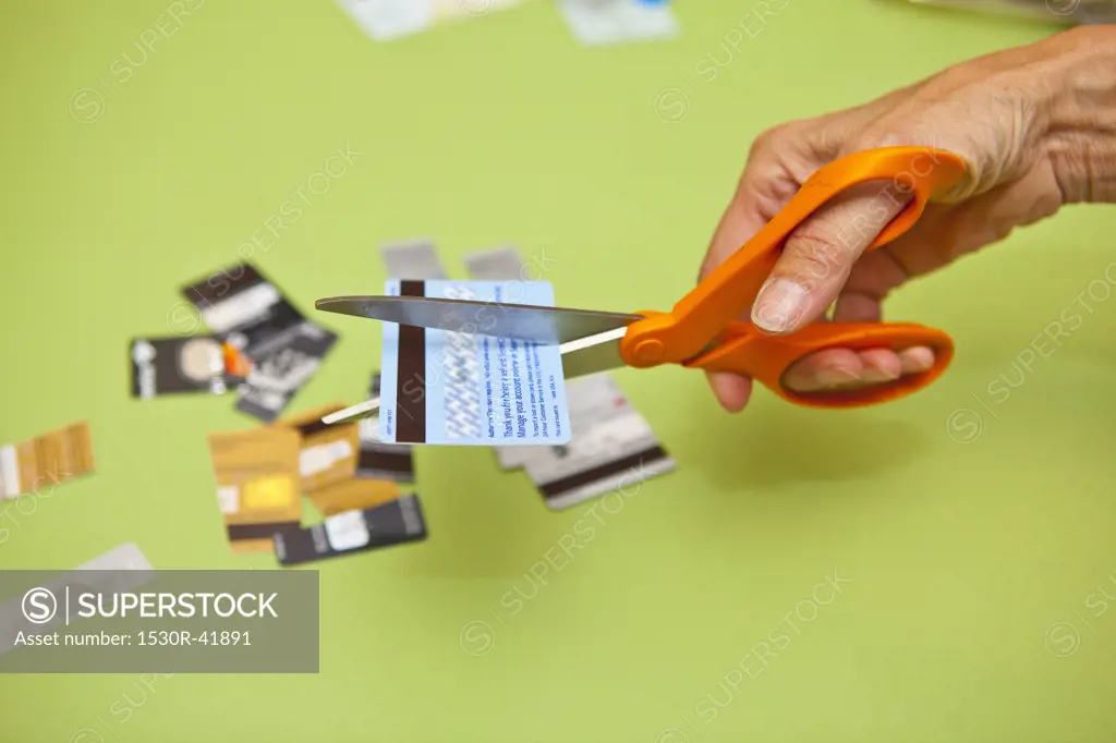 Hand using scissors to cut up credit cards