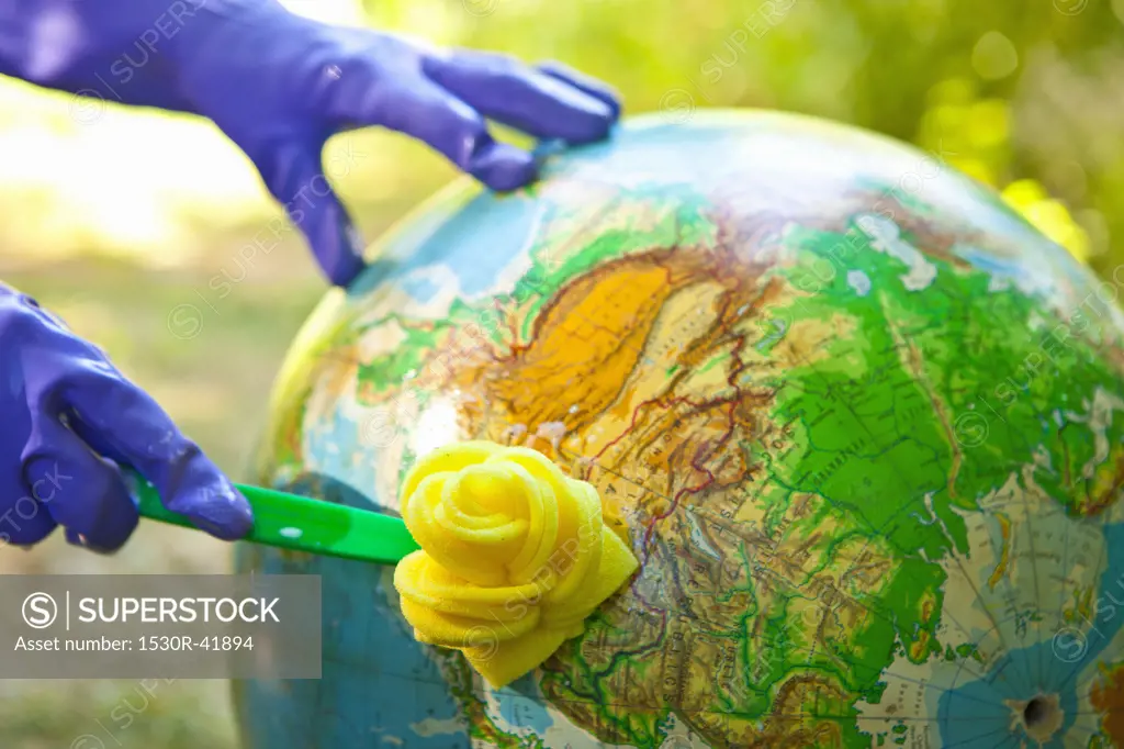 Woman wearing rubber gloves to scrub globe outdoors