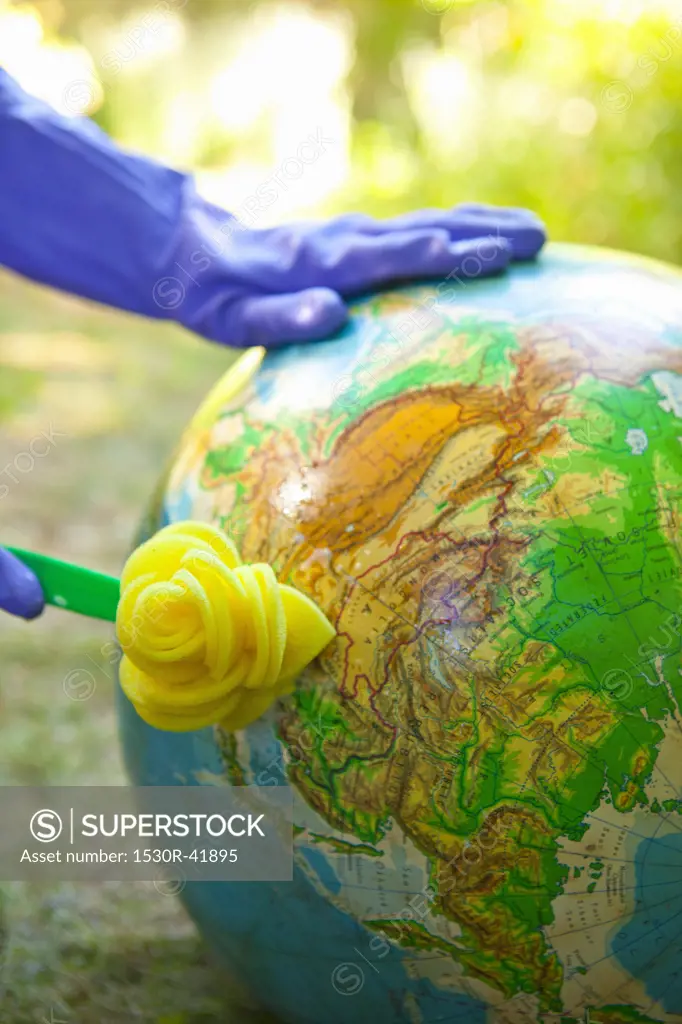 Woman wearing rubber gloves to scrub globe outdoors