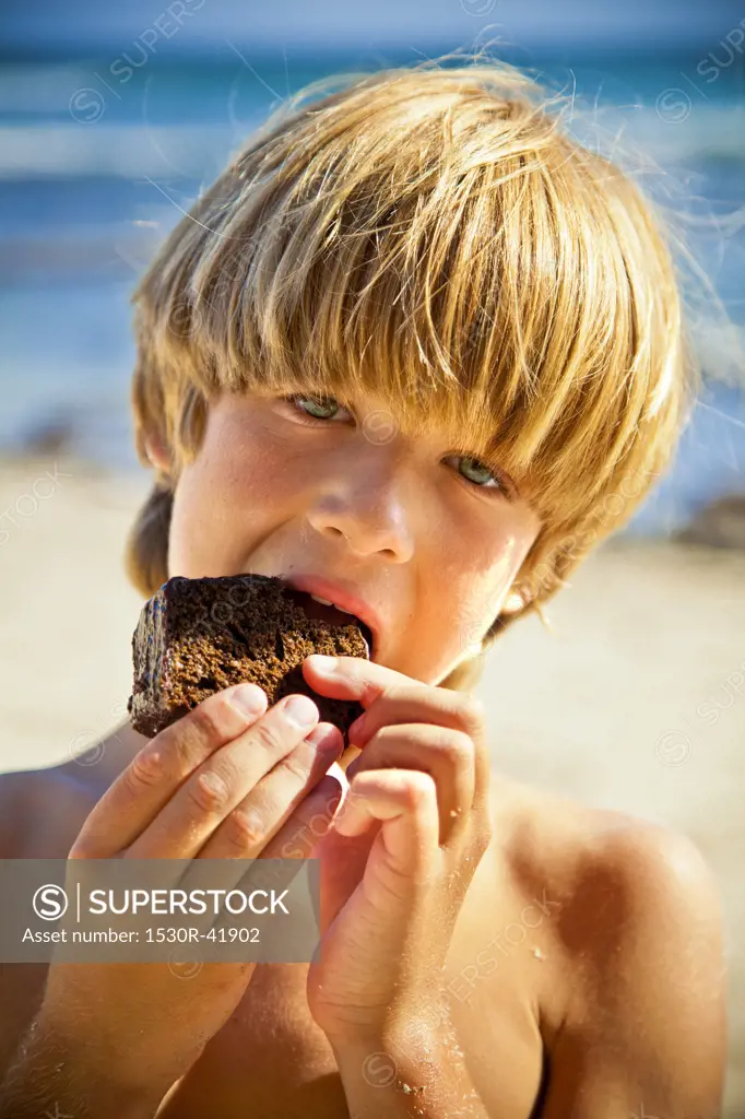 Young boy taking bite of large brownie