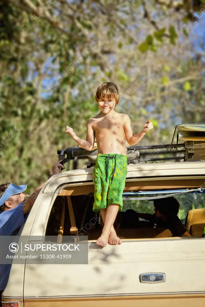 Boy standing on back of car