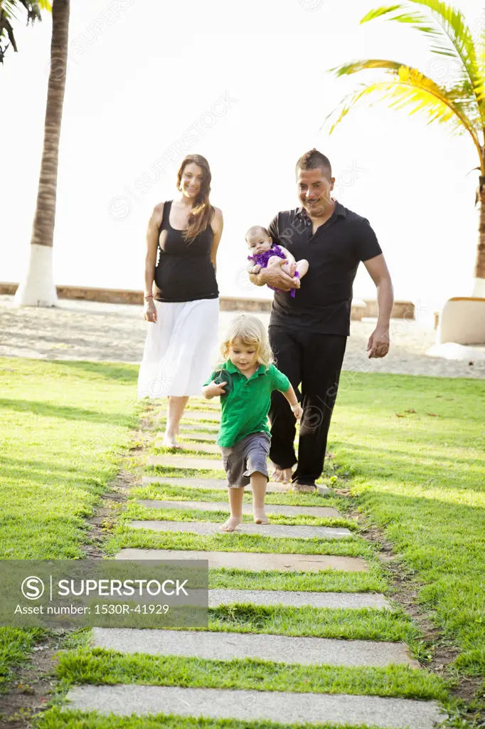 Woman and man holding baby with young boy outdoors