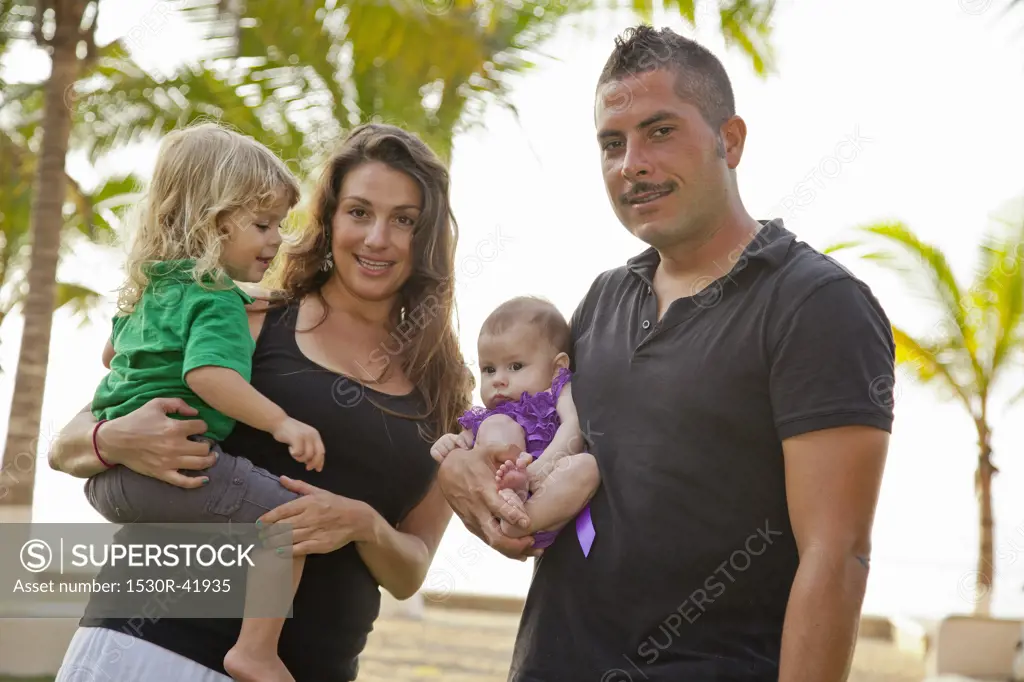 Man and woman holding baby and young child outdoors