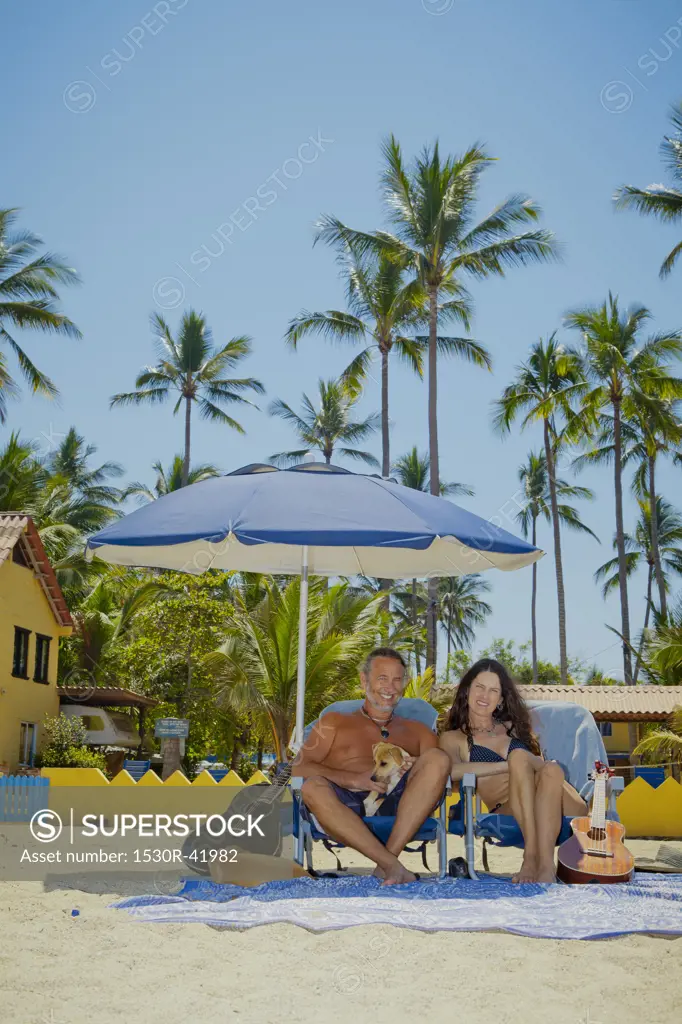 Happy man and woman in beach chairs with guitars and dogs,  Sayulita, Mexico