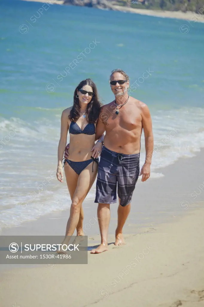 Man and woman walking on beach in swim suits,  Sayulita, Mexico