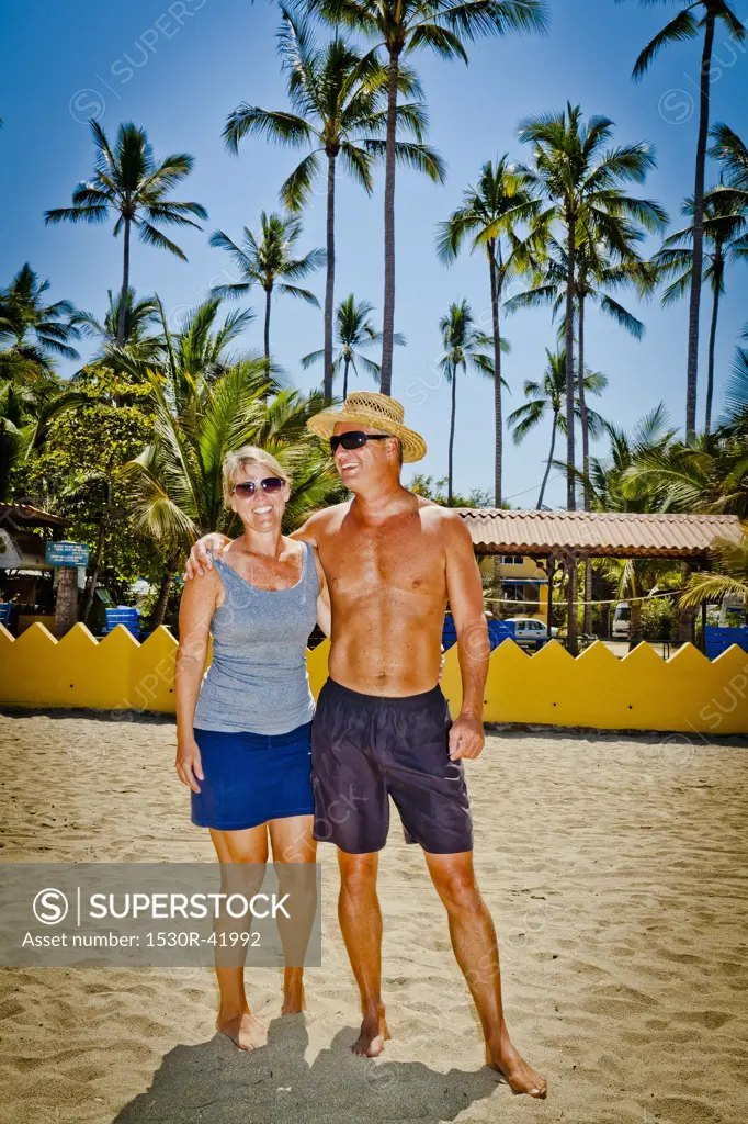Man and woman arm in arm on beach near palm trees,  Sayulita, Mexico
