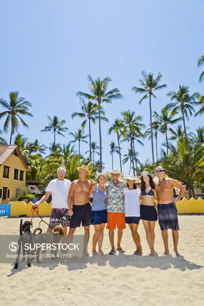 Seven adults standing on beach with dogs near palm trees,  Sayulita, Mexico