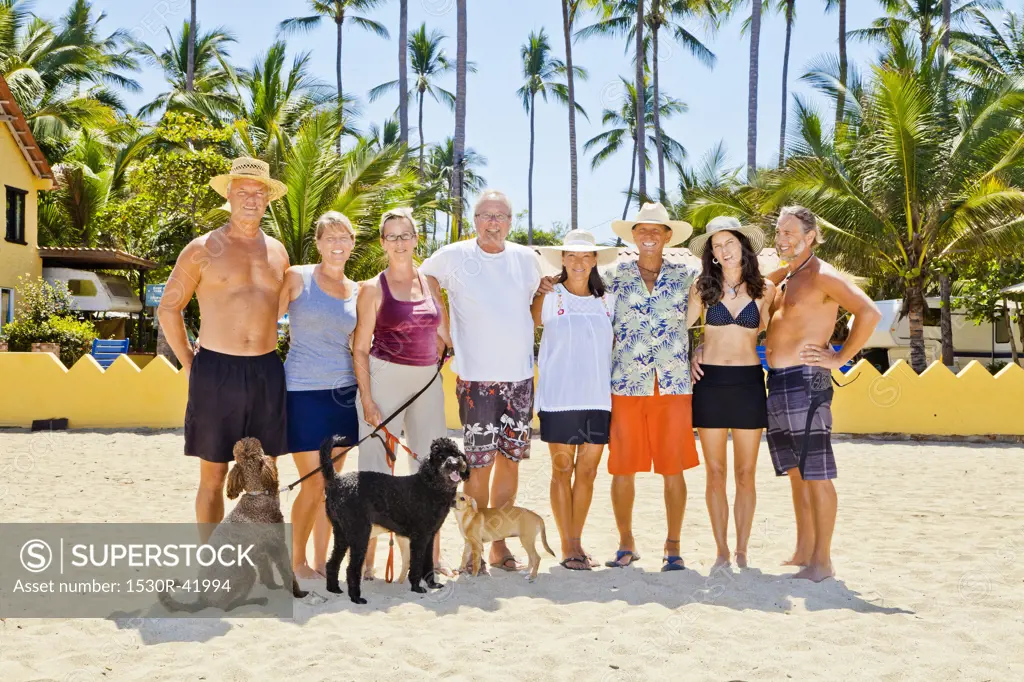 Seven adults standing on beach with dogs near palm trees,  Sayulita, Mexico