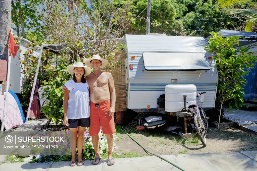 Man and woman standing in garden with camper,  Sayulita, Mexico