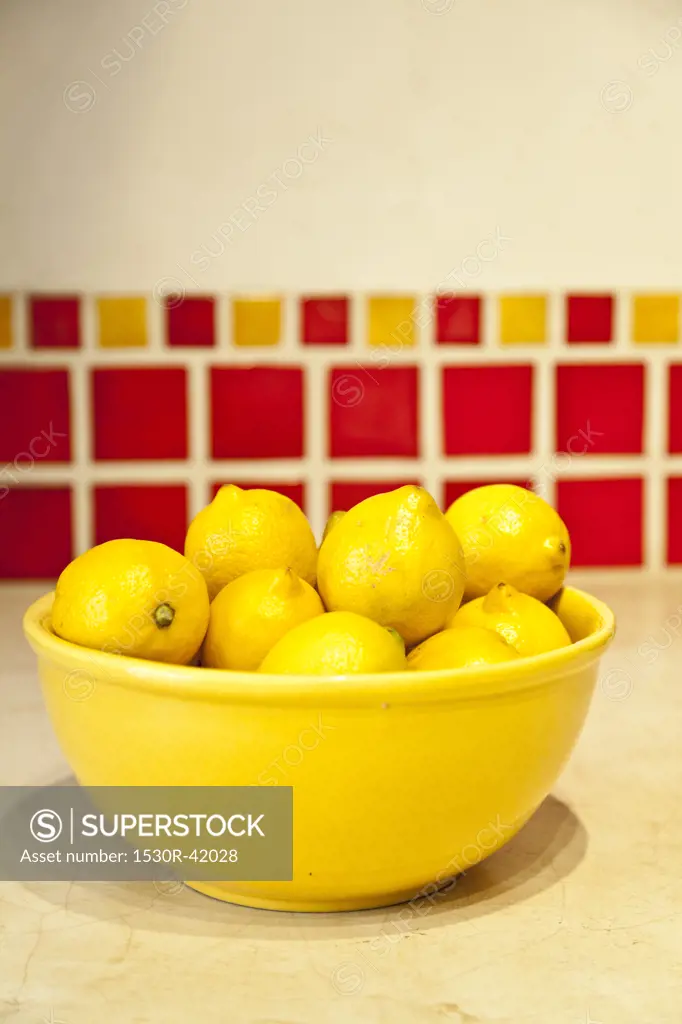 Bowl of lemons on counter with red tiles behind