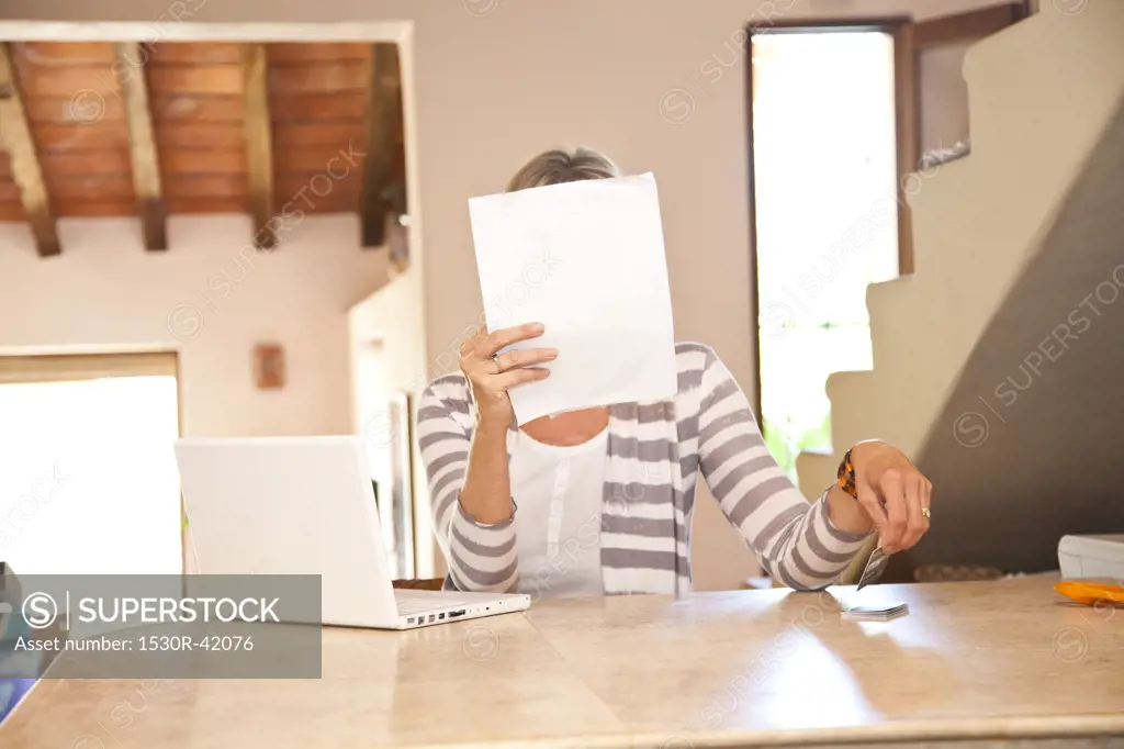 Woman in home office holding bills