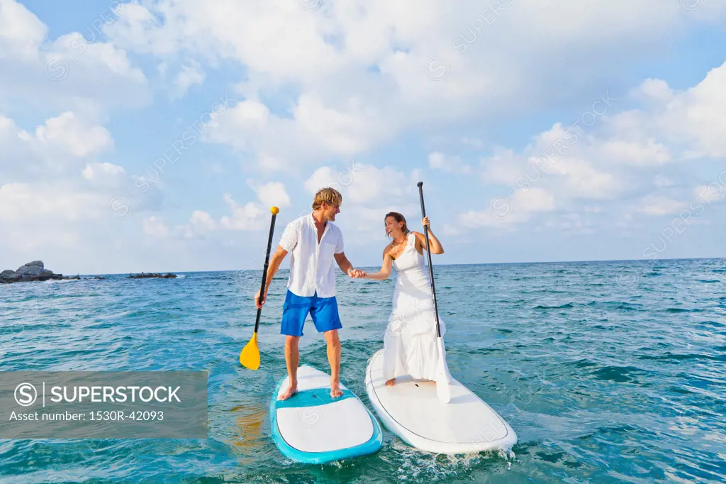 Dressed up mad and woman riding paddle boards