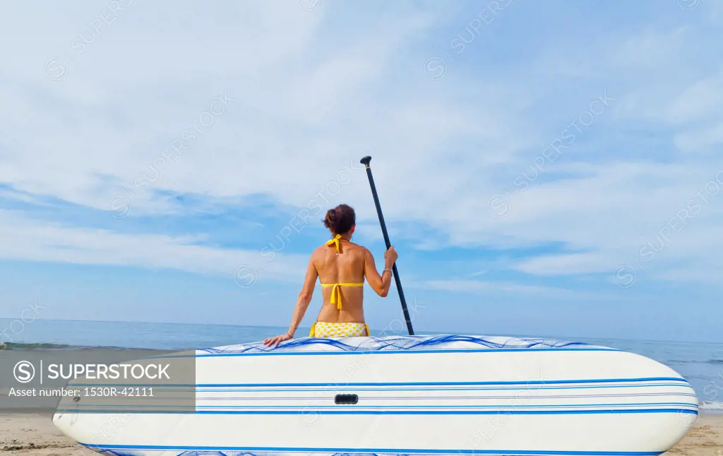 Woman on beach with paddle board