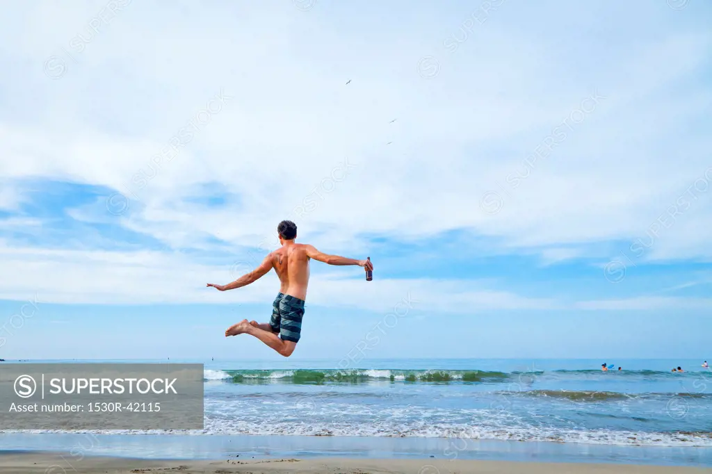 Man leaping in air on beach