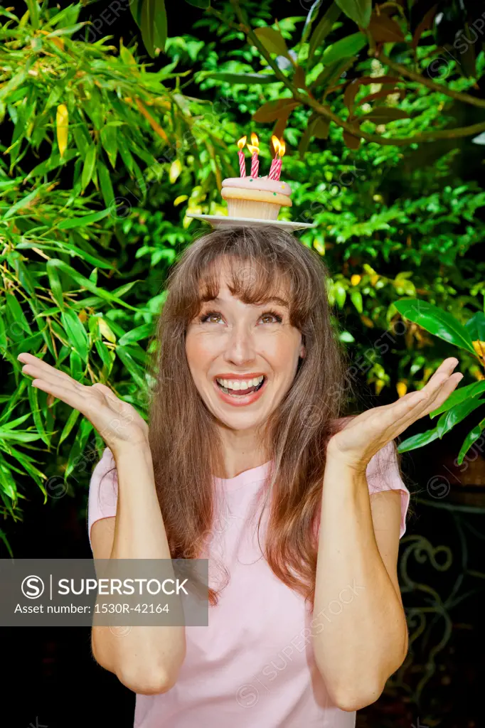 Woman with birthday cupcake on head
