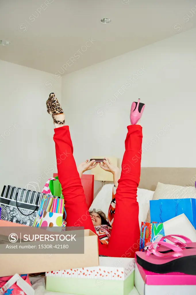 Woman on bed surrounded by shopping bags