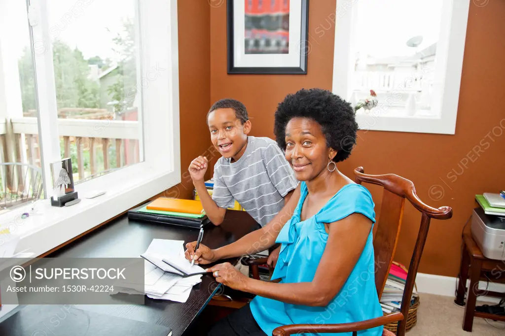 Woman working at home office with son