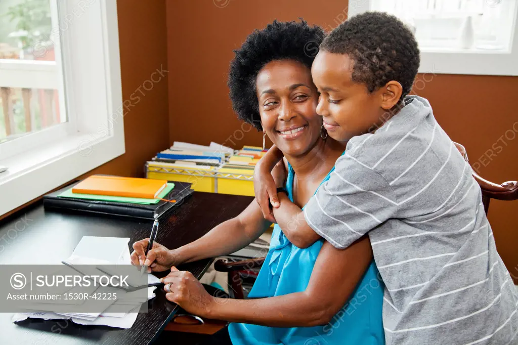 Woman working at home office with son