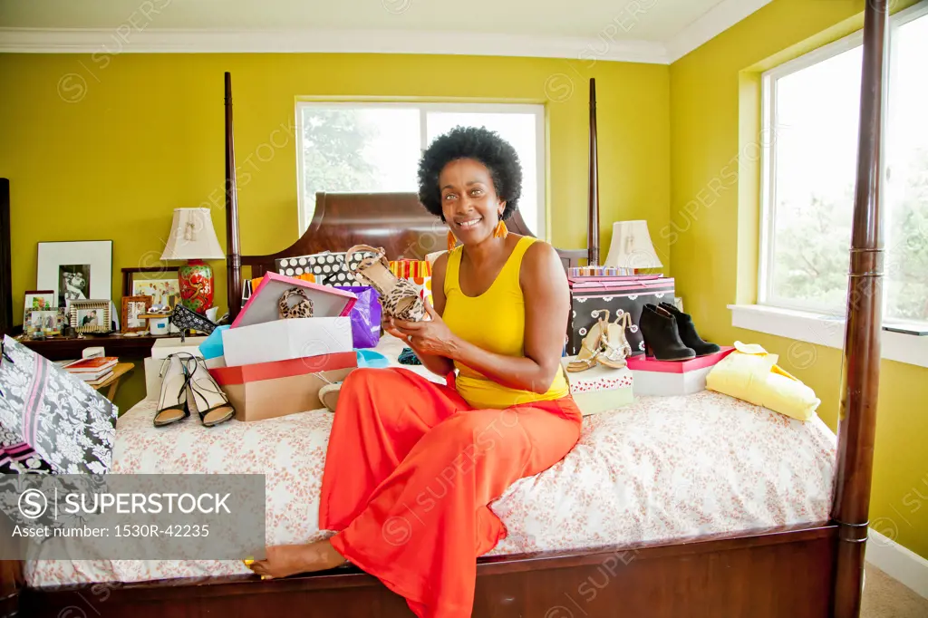 Woman on bed with shopping bags and shoes