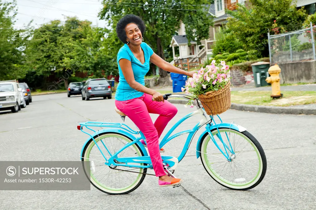 Woman riding retro bicycle with flower basket