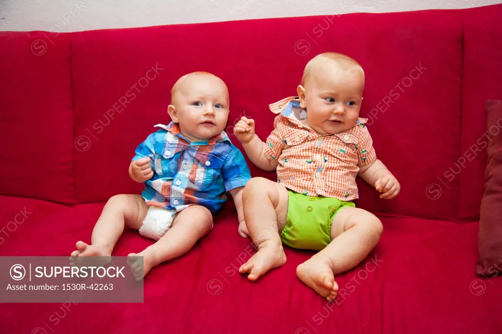 Two babies on red sofa