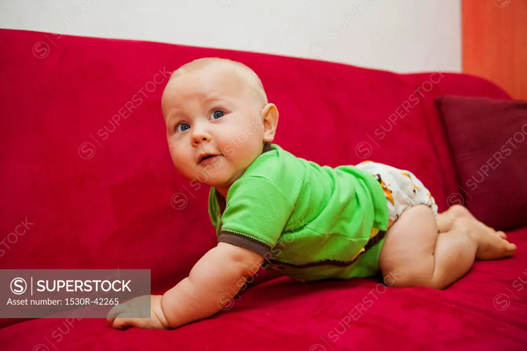 Baby crawling on red sofa