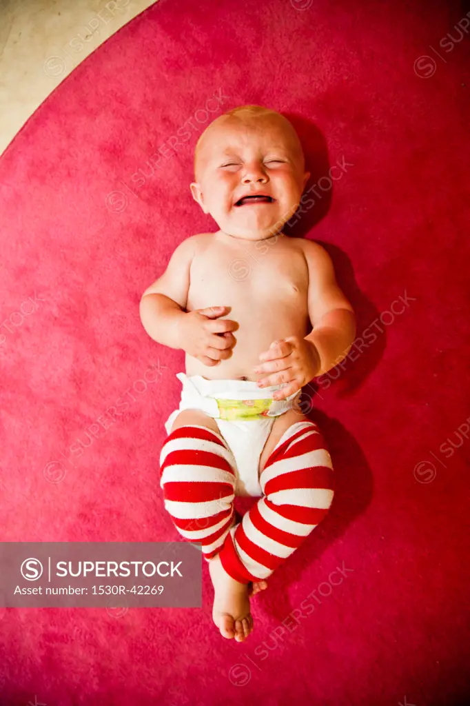 Crying baby on pink rug