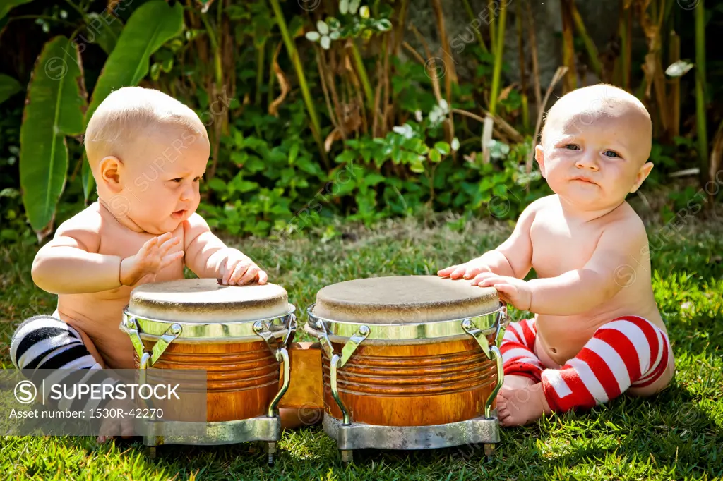 Twin babies playing drums outdoors