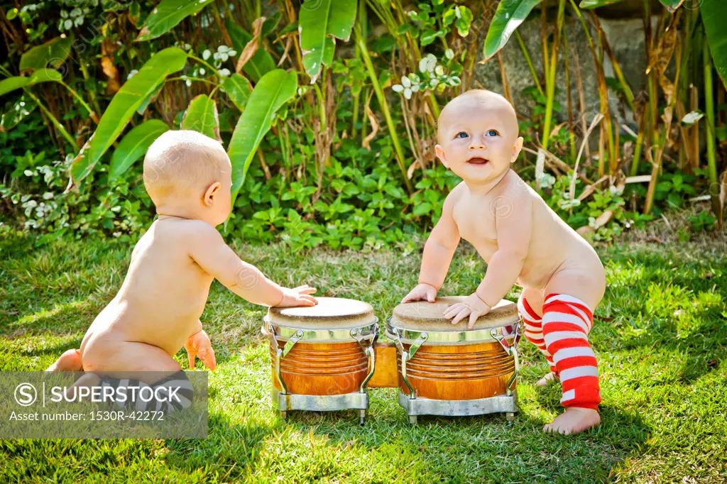 Twin babies playing drums outdoors