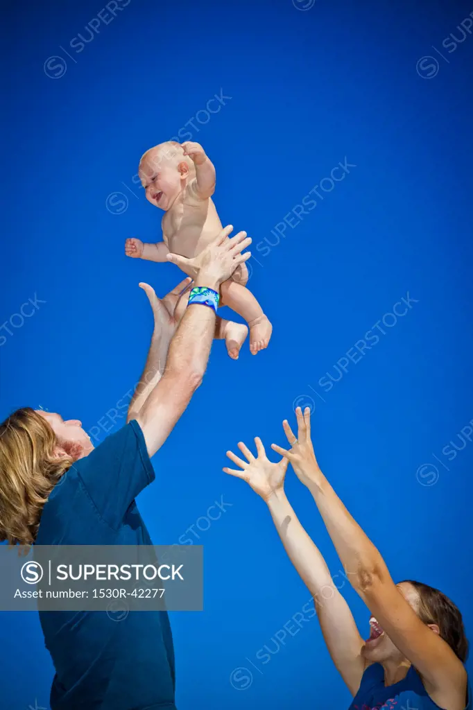 Parents holding baby up in air