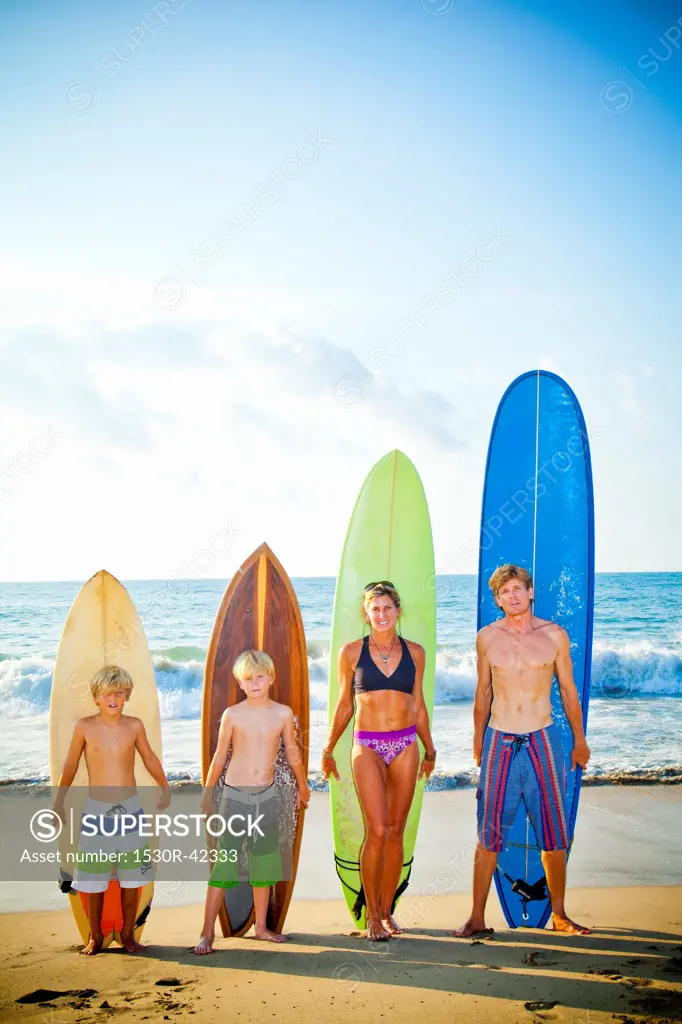 Family standing on beach with surfboards