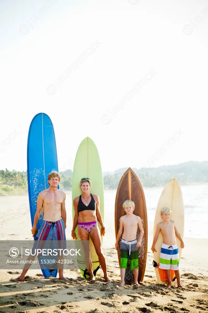Family standing on beach with surfboards