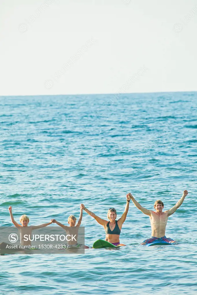 Family of four on surfboards in water