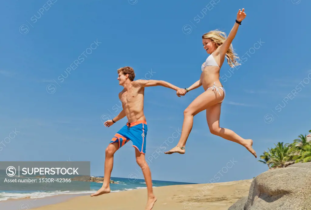 Young man and woman running on beach