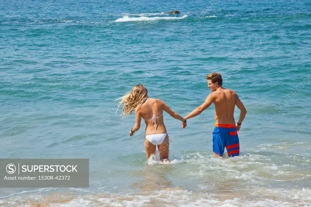 Young man and woman standing in surf