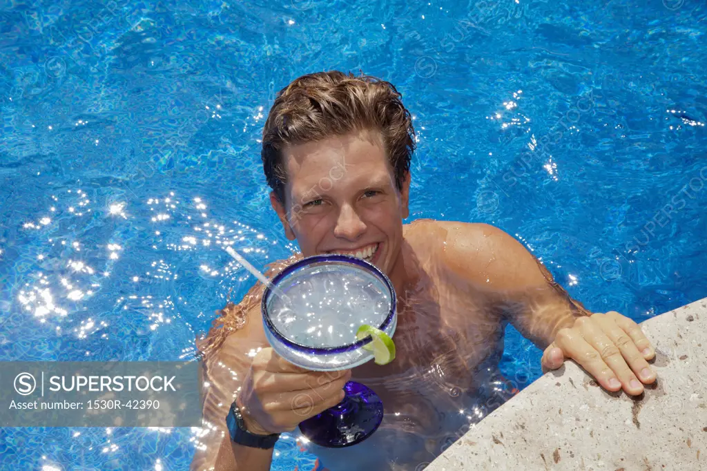 Young man in pool holding cocktail