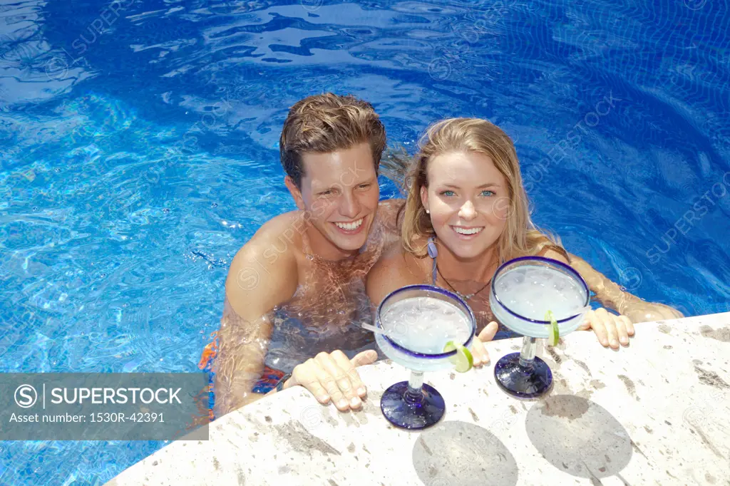 Young couple with cocktails in pool